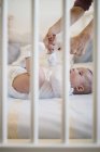 Cultivo padres manos jugando con el bebé en la cama - foto de stock