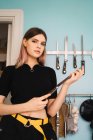 Portrait of young woman posing with knife and looking at camera in kitchen — Stock Photo