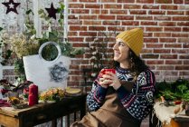 Portrait of smiling woman drinking hot beverage in floral atelier — Stock Photo