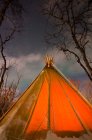 Tenda illuminata con falò nella foresta notturna — Foto stock