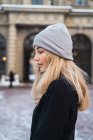 Вид збоку на стомлену блондинку позує в зимовому місті — стокове фото