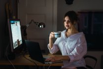 Ritratto di donna seduta al computer portatile con coppa a casa . — Foto stock
