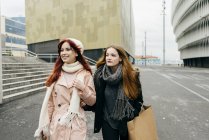Portrait of two young women walking together with confidence on city street. — Stock Photo