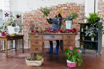 Vista laterale di fiorista organizzare fiori a tavola in atelier floreale — Foto stock