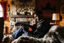 Seitenansicht eines Mannes, der zu Hause auf dem Sofa Gitarre spielt — Stockfoto