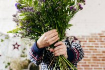 Female in knitted sweater holding bouquet in front of face. — Stock Photo