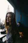 Giovane donna bruna guardando oltre la spalla alla macchina fotografica nel caffè della città — Foto stock
