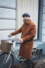 Вид збоку бородатого чоловіка з вінтажним велосипедом, що йде по вулиці — стокове фото