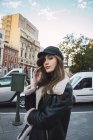 Красива жінка в кепці, що йде по вулиці і дивиться на камеру — стокове фото