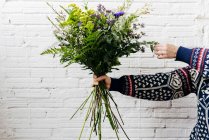 Crop hand adjusting bouquet over white brick wall — Stock Photo