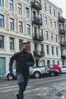 Sportlicher Mann in warmer Sportkleidung läuft auf der Straße — Stockfoto