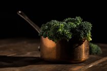 Bodegón de broccolis bimi fresco en maceta de salsa de cobre en mesa de madera rústica - foto de stock