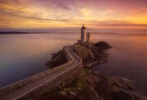 Aerial view to road to lighthouse built on hill at seaside in sunset lights. — Stock Photo