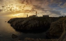 Далекий вид на маяк, установленный на холме на берегу моря при свете заката . — стоковое фото