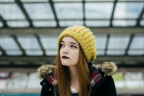 Ritratto di giovane donna in cappotto e cappello a maglia in posa nel centro commerciale — Foto stock