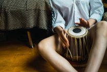 Crop female playing tabla percussion and sitting on floor. — Stock Photo