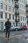 Lächelnder Jogger läuft auf Stadtstraße mit geparkten Autos — Stockfoto