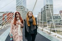 Frontansicht von zwei lächelnden Frauen, die auf Brücke gehen — Stockfoto