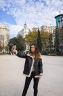 Donna vestita di caldo cappotto scattare selfie con smartphone al parco — Foto stock