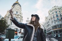 Smiling pretty woman taking selfie with smartphone at street scene — Stock Photo