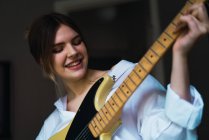 Портрет улыбающейся женщины, играющей на гитаре — стоковое фото