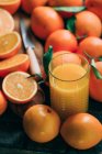 Vista de baixo ângulo de laranjas fatiadas frescas e vidro de suco de laranja — Fotografia de Stock