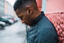 Porträt eines sportlichen Mannes mit Kopfhörern, der auf der Straße Musik hört — Stockfoto