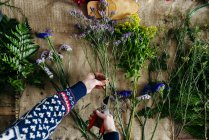 Schnitthände schneiden Blumen über Leinenstoff. — Stockfoto
