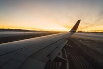 Vue de l'aile de l'avion à l'aéroport dans les lumières du coucher du soleil . — Photo de stock
