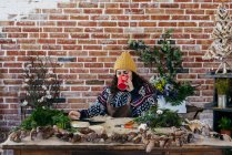 Ritratto di donna che beve caffè a tavola e chiacchiera su tavoletta in atelier floreale — Foto stock