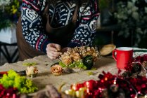 Crop female in apron making floral composition on sacking fabric — Stock Photo