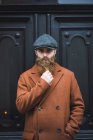 Портрет вдумчивого бородатого человека, смотрящего в камеру и держащего бороду — стоковое фото