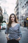 Junge brünette Frau posiert auf urbaner Straße und schaut in die Kamera — Stockfoto