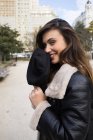 Sorridente giovane donna bruna in posa con tappo al parco cittadino — Foto stock