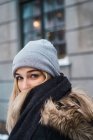 Hübsche junge sinnliche Frau steht auf der verschneiten Straße und blickt über die Schulter in die Kamera — Stockfoto