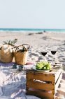 Vista idílica de las gafas de vino y la uva en el cajón en la playa - foto de stock