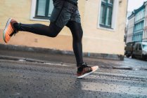 Crop male legs running at street scene — Stock Photo