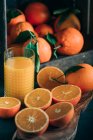 Натюрморт зі свіжих апельсинів та скла з апельсиновим соком — стокове фото