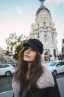 Brunette girl in cap walking at street and looking at camera — Stock Photo