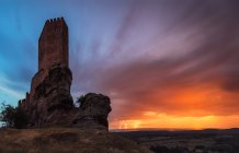 Panoramic view to castle tower built on hill on background of sunset sky — Stock Photo