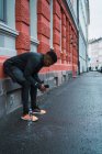Sportlicher Jogger lehnt sich nach dem Laufen mit Smartphone in der Hand an Fassade — Stockfoto