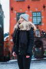 Side view of blonde woman wearing winter outfit posing on winter street — Stock Photo