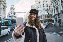 Brunette femme prendre selfie dans la rue — Photo de stock