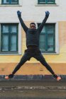 Retrato do homem que se estende extensamente pernas e braços enquanto salta na rua — Fotografia de Stock