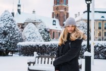 Портрет блондинки в теплому вбранні позує в зимовому місті і дивиться на камеру — стокове фото