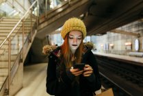 Porträt einer jungen Frau, die in der U-Bahn steht und ihr Smartphone benutzt — Stockfoto