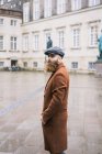 Homem barbudo vestindo casaco e boné andando na cidade — Fotografia de Stock