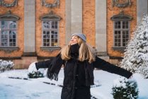 Portrait of blonde woman posing widely outstretched arms in winter town — Stock Photo