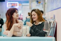 Vista lateral de dos mujeres sonrientes tomando cócteles en la cafetería - foto de stock