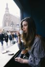 Vue latérale de la fille brune buvant du café par fenêtre au café — Photo de stock